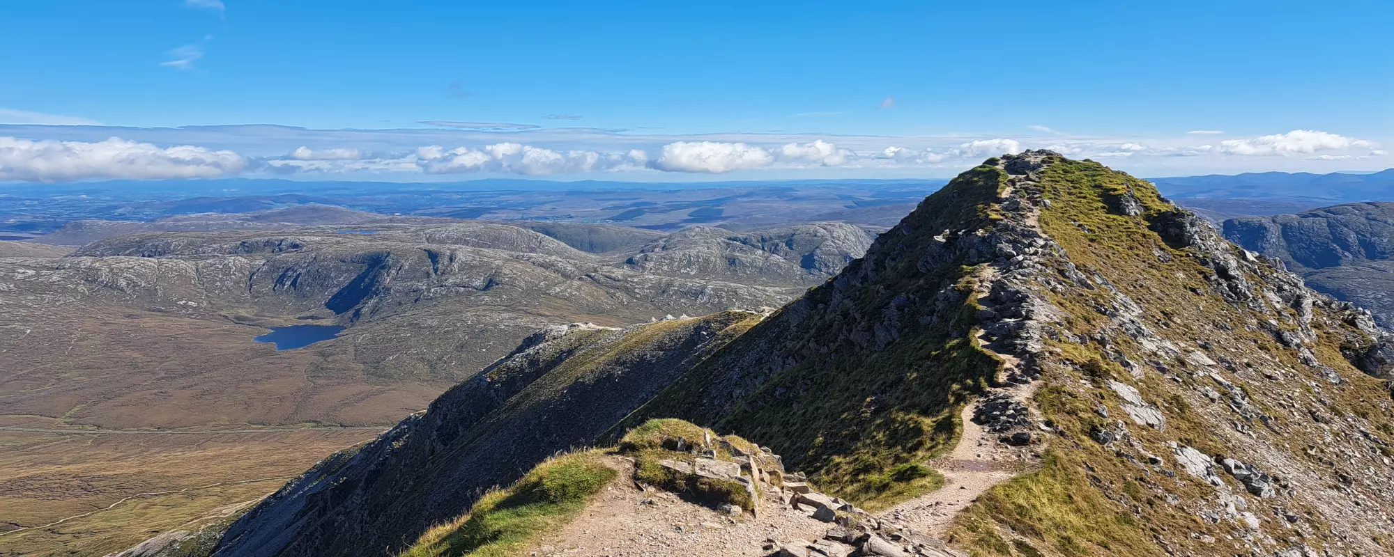 Top of mountain with view of surrounding hills and lake.
