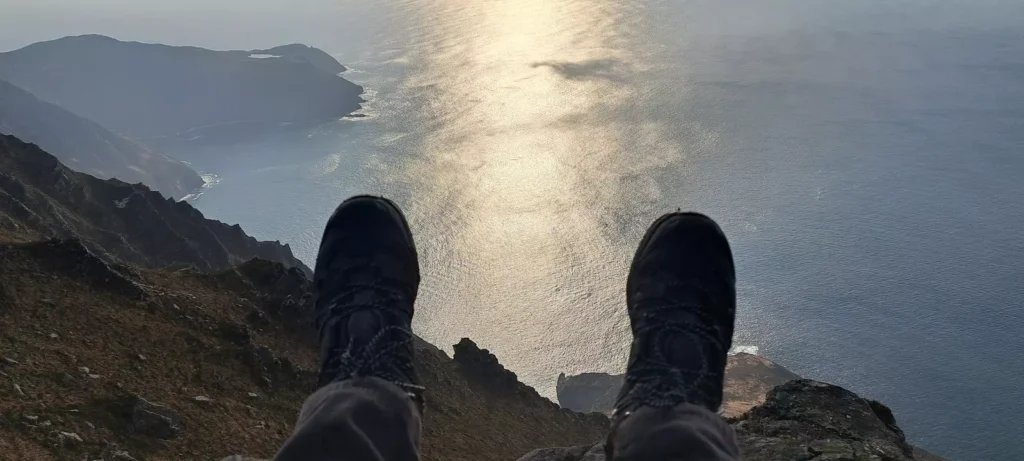 Hikers feet with view out over sea below.