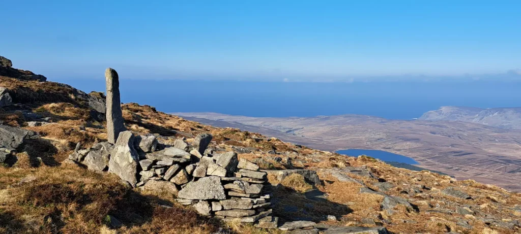 Stone ruin located on top of a mountain with view of sea in the distance.