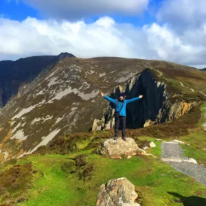 Hiker standing on rock with arms outstretched
