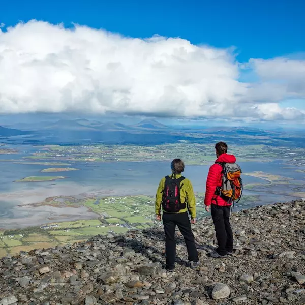 Two Hikers on rocky summit looking out over bay with small islands