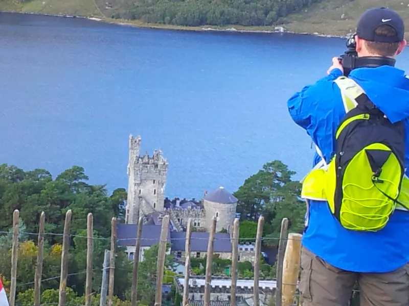 Hiker taking photograph of Castle and lake.