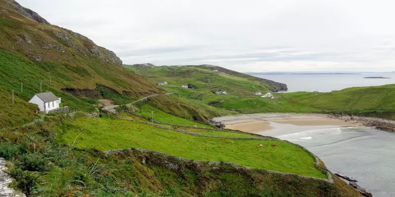 Sandy beach at the end of a small bay surrounded by hills.