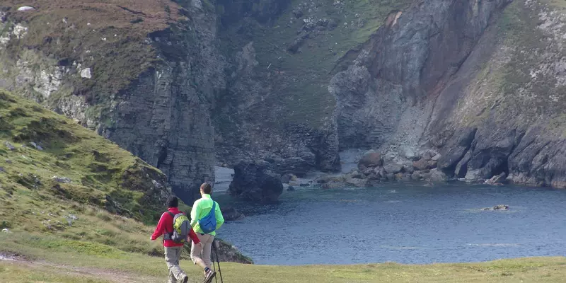 Two hikers walking along the coast.